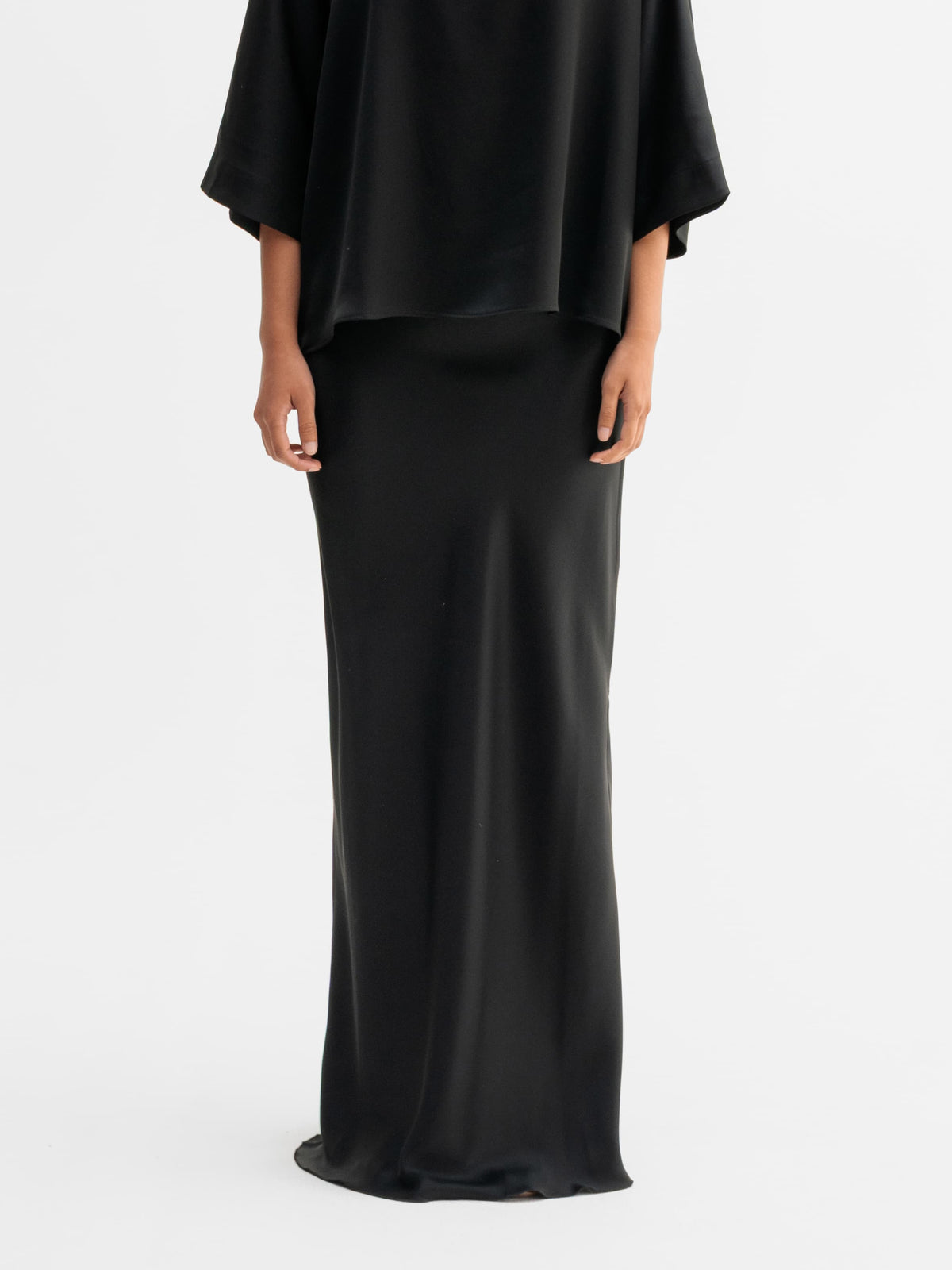 Model wearing Ahlvar Gallery Hana long logo satin skirt in Black