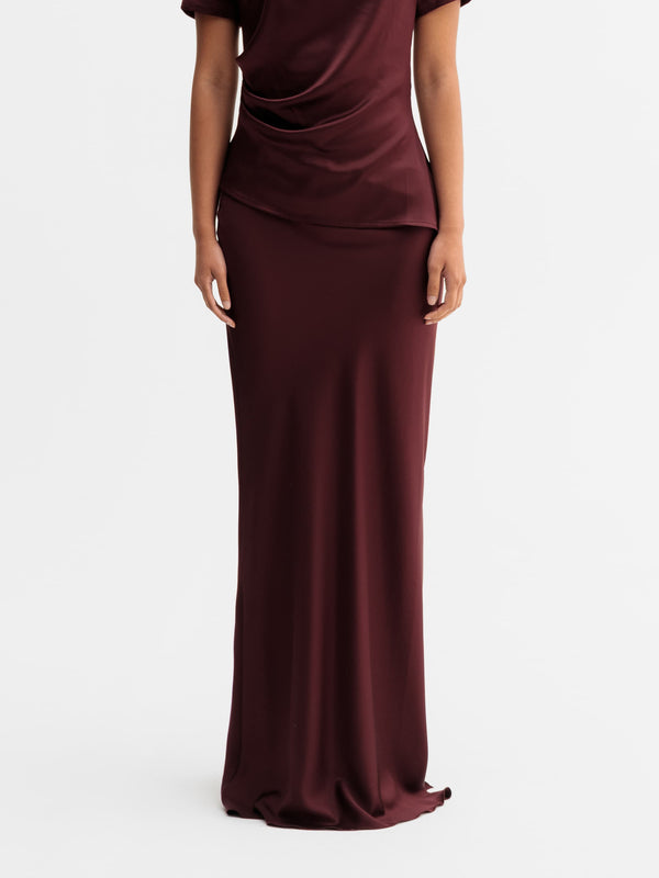 Model wearing Ahlvar Gallery Hana long logo satin skirt in Burgundy