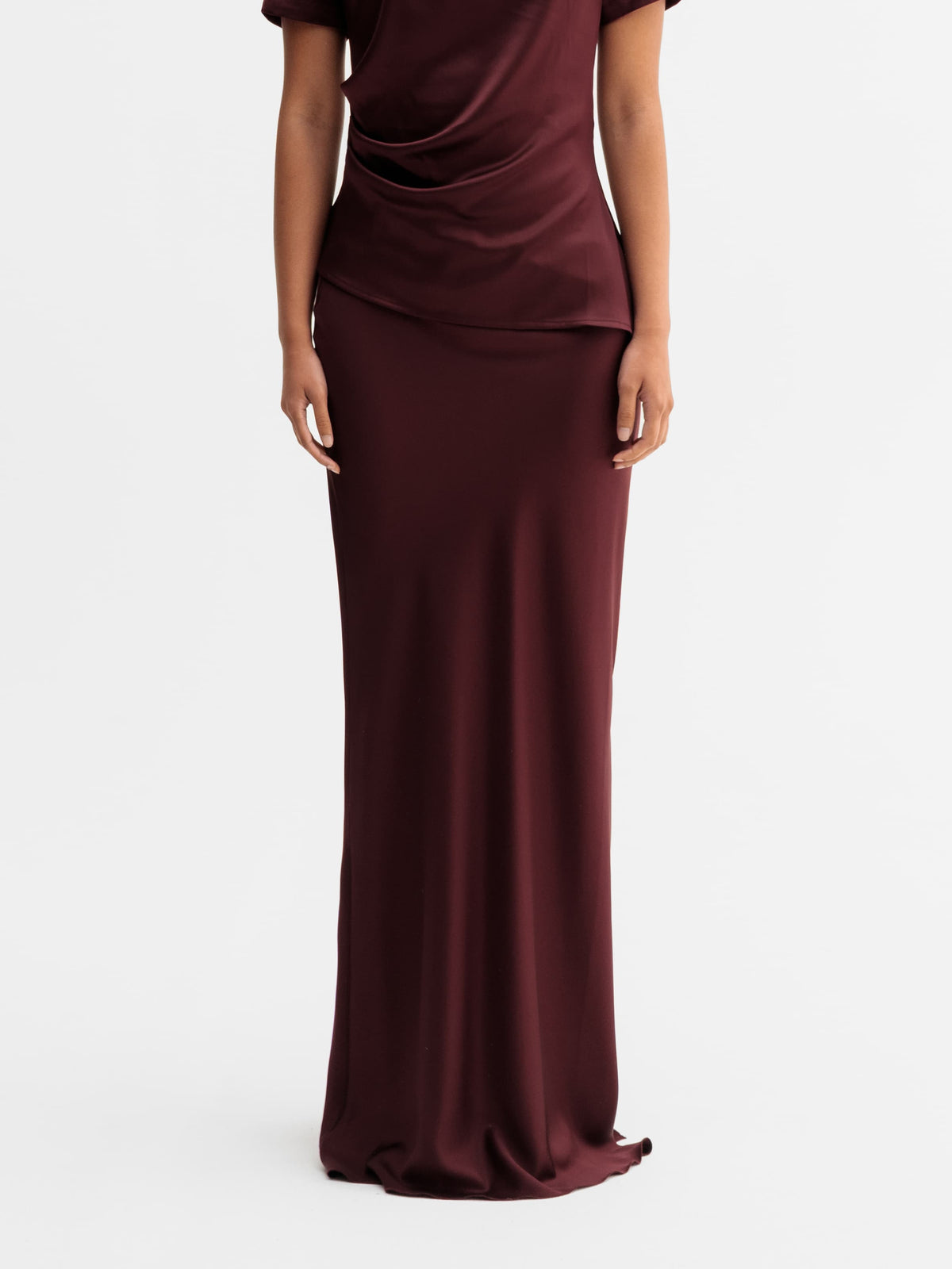 Model wearing Ahlvar Gallery Hana long logo satin skirt in Burgundy
