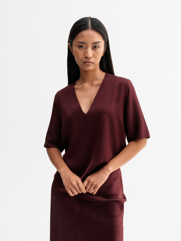 Model wearing Ahlvar Gallery Yoli v-neck silk blouse in Burgundy