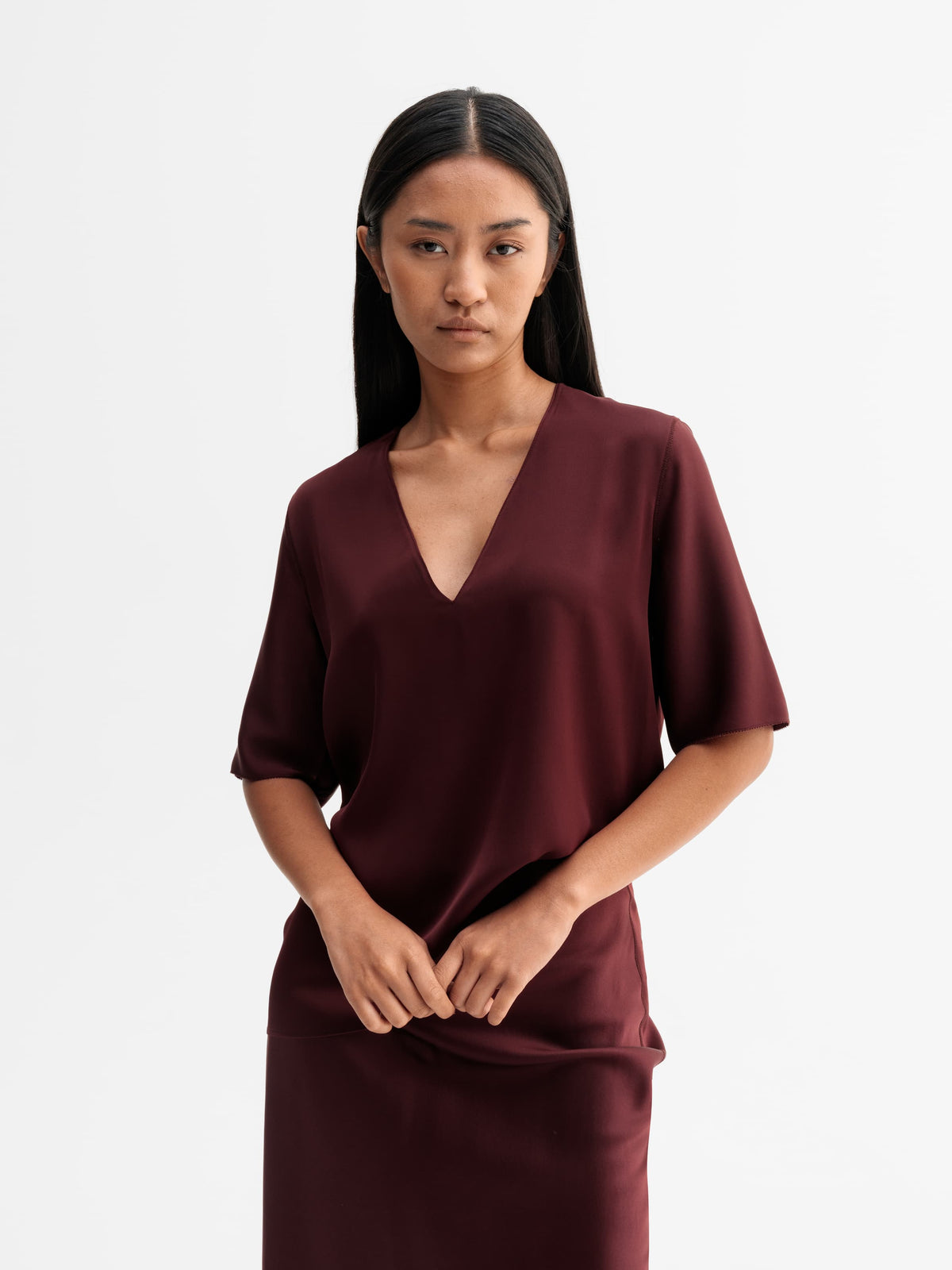 Model wearing Ahlvar Gallery Yoli v-neck silk blouse in Burgundy