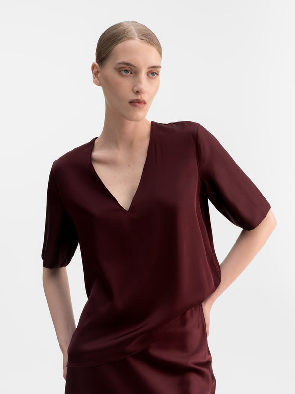 Model wearing Ahlvar Gallery Yoli v-neck silk blouse in Burgundy
