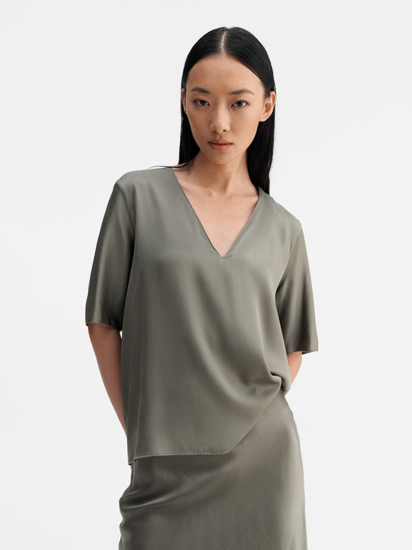 Model wearing Ahlvar Gallery Yoli v-neck silk blouse light military